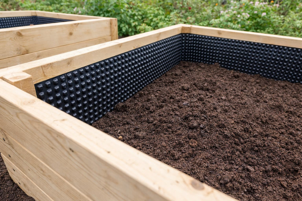 Фото фрагмента внутренней стороны грядки из досок с применением профилированной мембраны